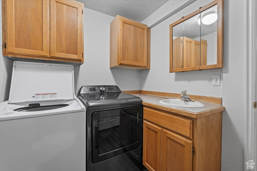 Laundry area with cabinet space, washer and dryer, and a textured ceiling