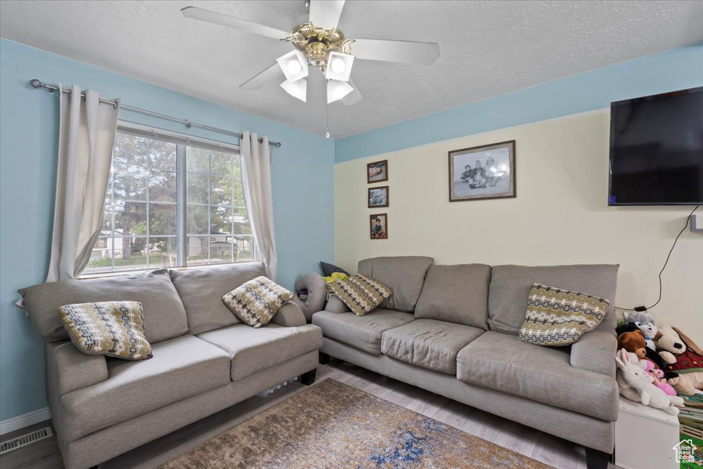 Living room featuring a ceiling fan, wood finished floors, and a textured ceiling