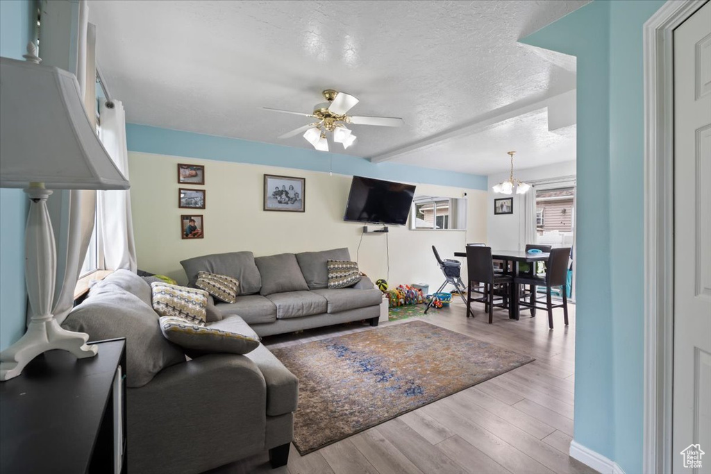 Living area featuring wood finished floors, a textured ceiling, a chandelier, and ceiling fan