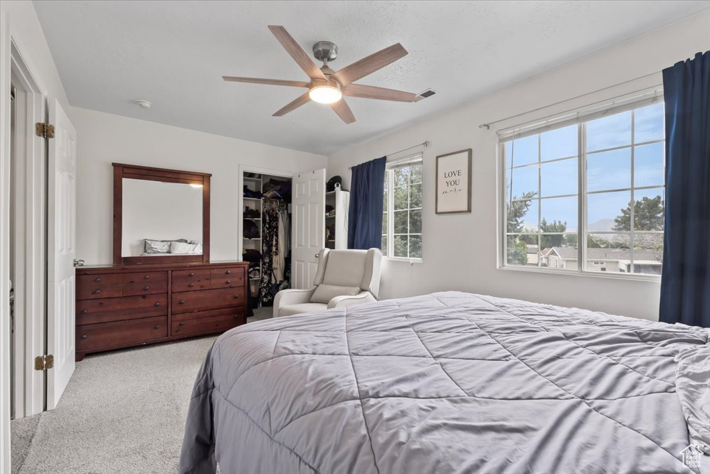 Carpeted bedroom with a ceiling fan, a spacious closet, and a closet