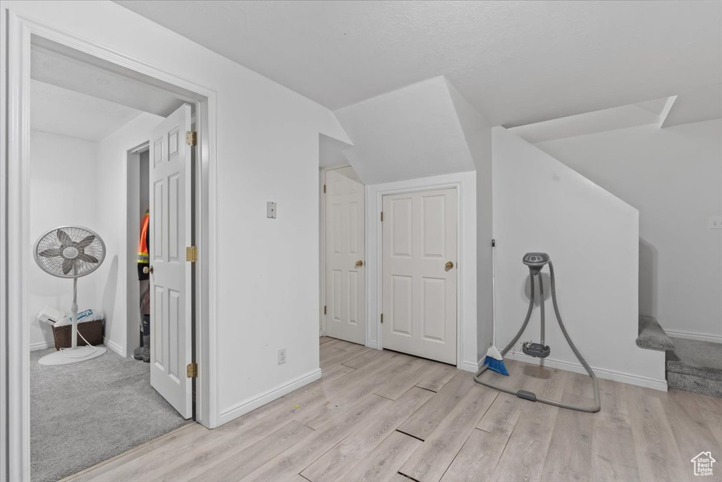 Additional living space featuring light wood-type flooring and vaulted ceiling
