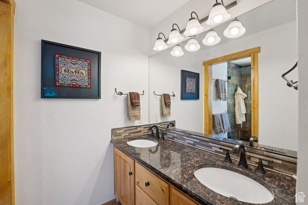 Bathroom featuring double vanity, backsplash, and a shower
