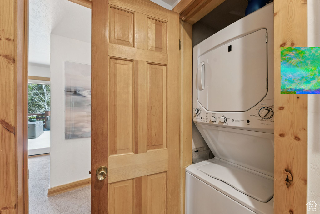 Laundry room featuring stacked washer / dryer and carpet floors