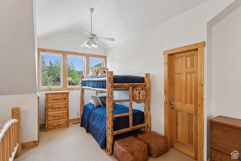 Bedroom with vaulted ceiling, light colored carpet, and a ceiling fan
