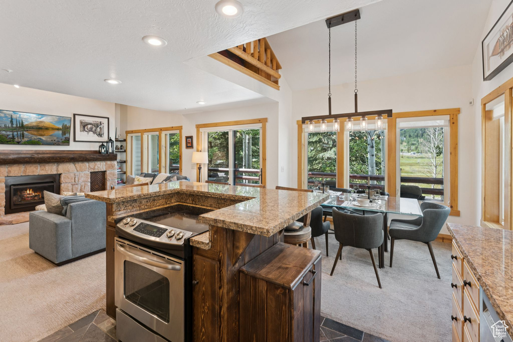 Kitchen with stainless steel electric stove, light stone countertops, open floor plan, a fireplace, and recessed lighting