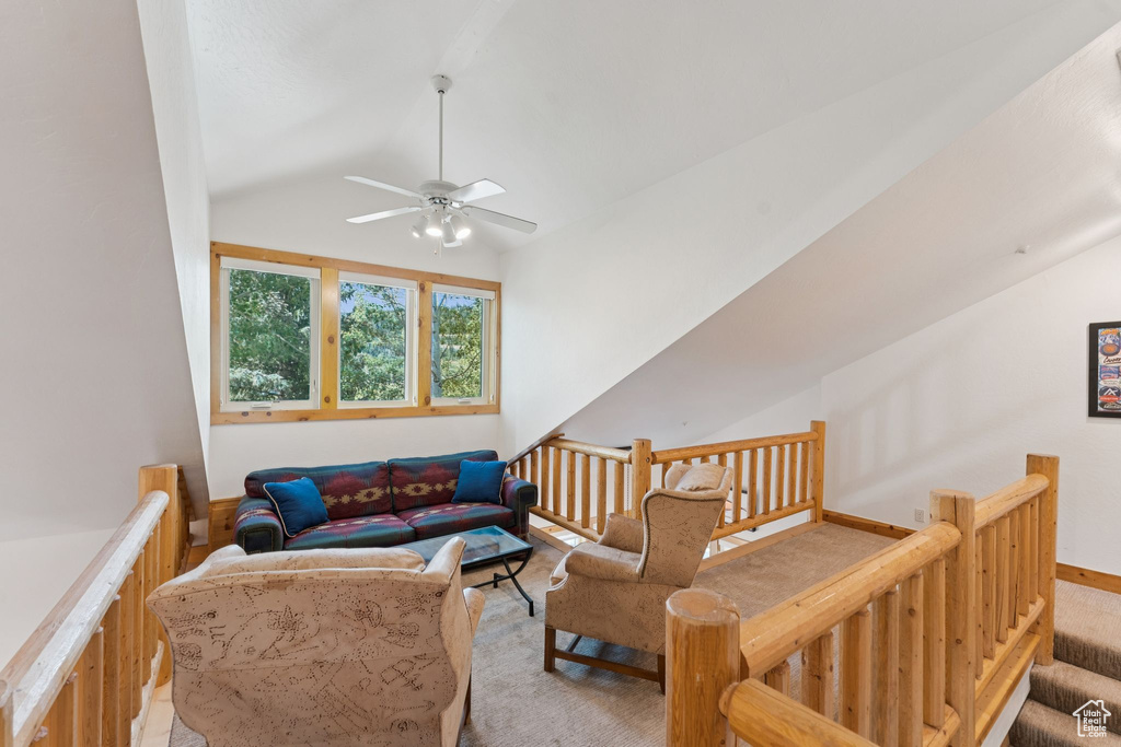 Living area with lofted ceiling, a ceiling fan, and light carpet