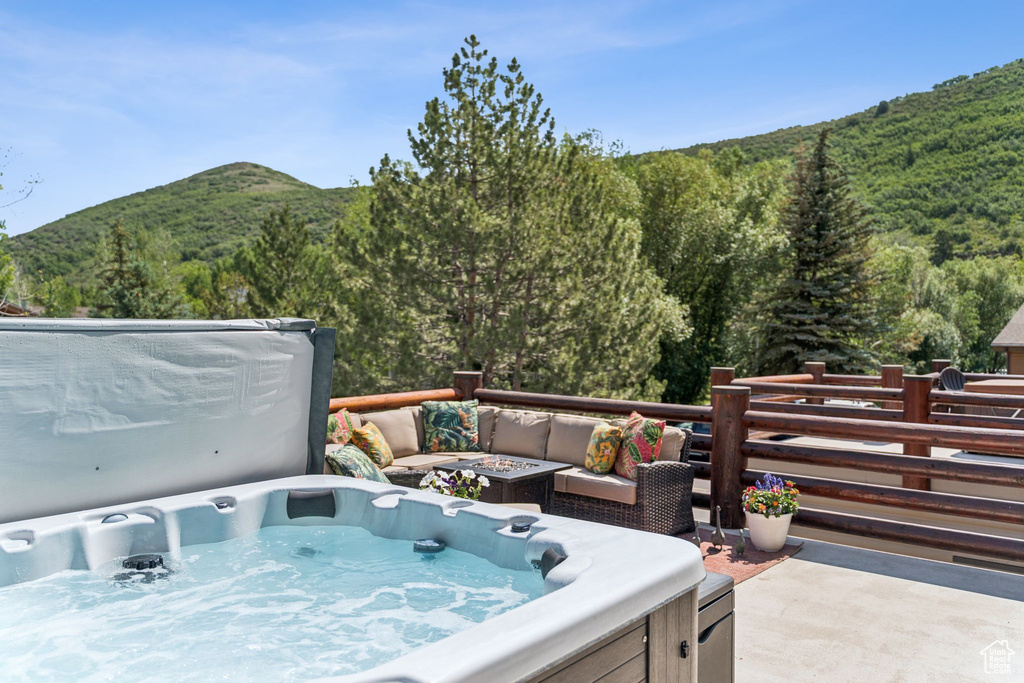Wooden terrace featuring a hot tub, a view of trees, and a mountain view