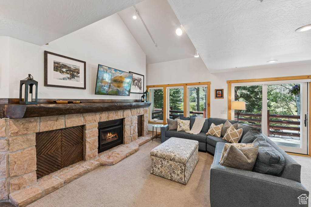 Carpeted living room with a stone fireplace, high vaulted ceiling, recessed lighting, and a textured ceiling