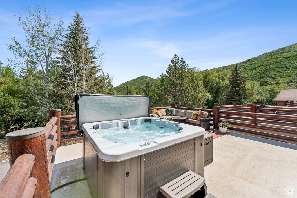 Deck with a hot tub, a forest view, and a mountain view