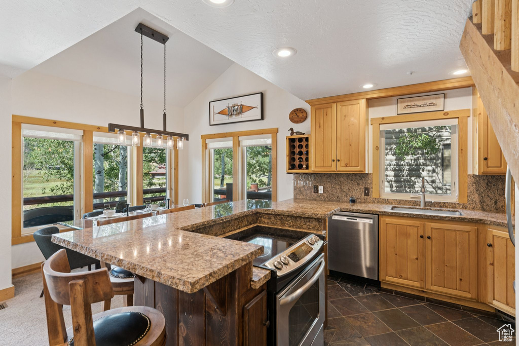 Kitchen featuring appliances with stainless steel finishes, backsplash, healthy amount of natural light, a kitchen bar, and lofted ceiling