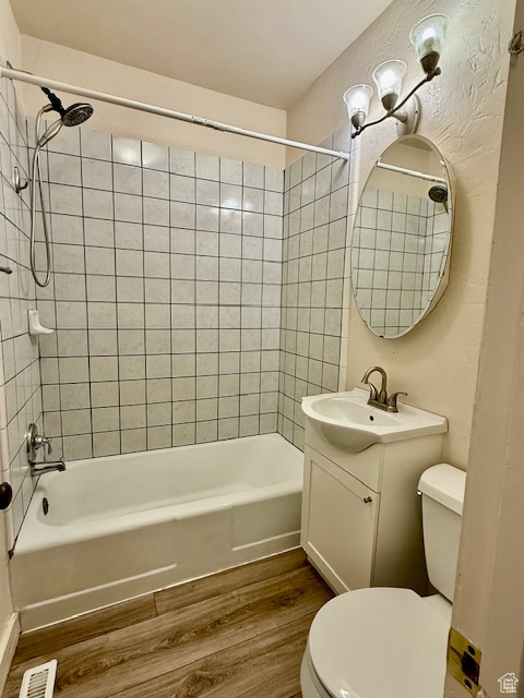 Bathroom with wood finished floors, vanity, and washtub / shower combination