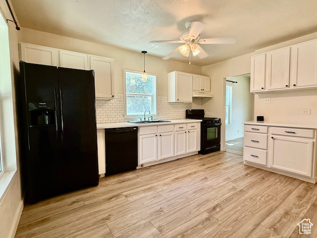Kitchen with black appliances, white cabinets, light wood finished floors, light countertops, and a textured ceiling