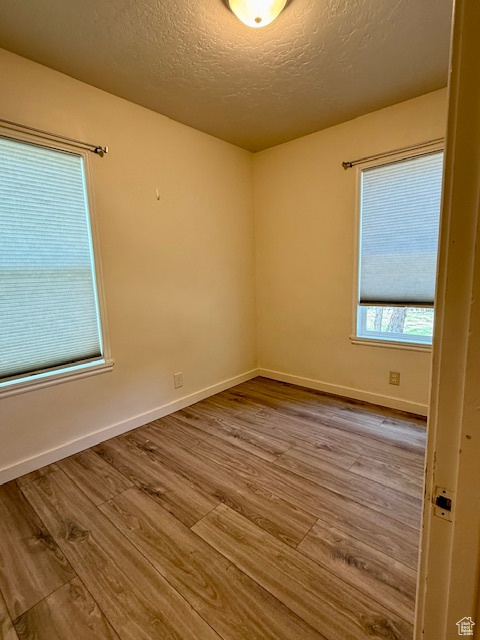 Unfurnished room featuring wood finished floors and a textured ceiling