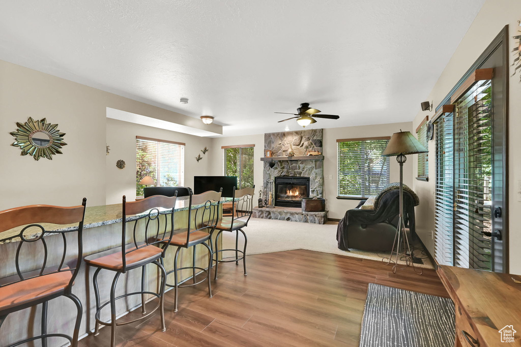 Living area featuring a ceiling fan, a stone fireplace, and wood finished floors