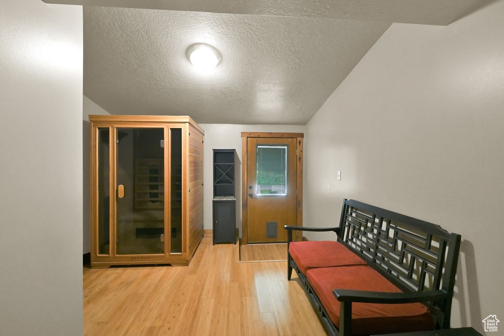 Sitting room featuring light wood finished floors, a textured ceiling, and vaulted ceiling
