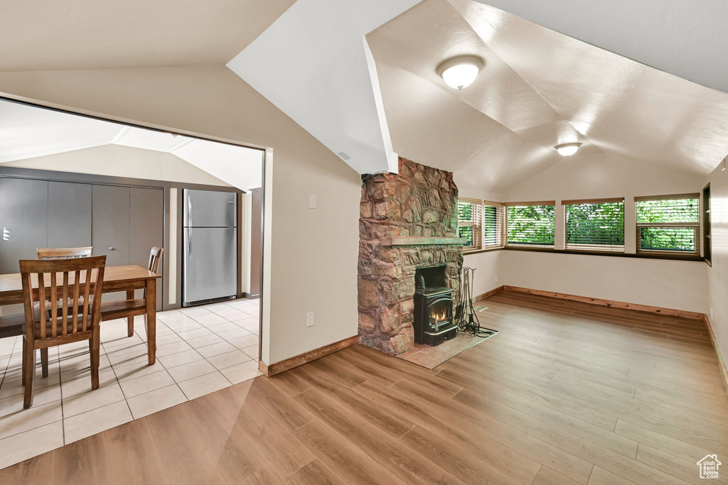 Unfurnished living room with vaulted ceiling, light wood-style floors, and a fireplace