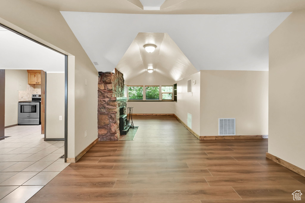 Unfurnished living room with a fireplace, light wood finished floors, and vaulted ceiling