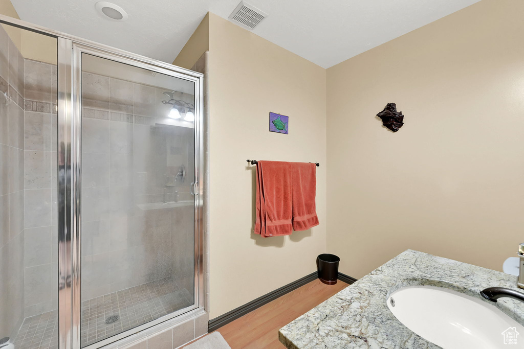 Bathroom featuring wood finished floors, a shower stall, and vanity