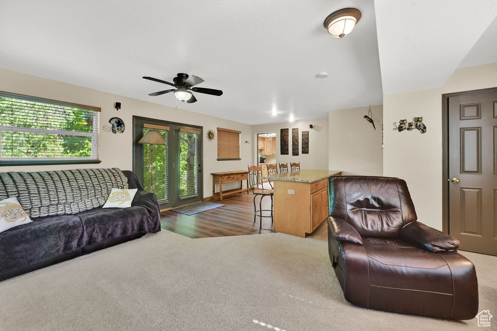 Carpeted living area with ceiling fan and wood finished floors