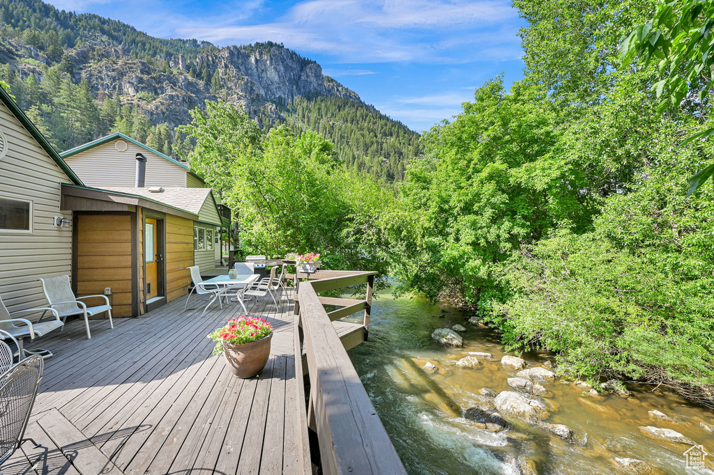 Deck with outdoor dining area, a view of trees, and a mountain view