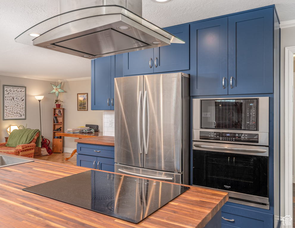 Kitchen featuring wood counters, black appliances, island range hood, blue cabinets, and ornamental molding