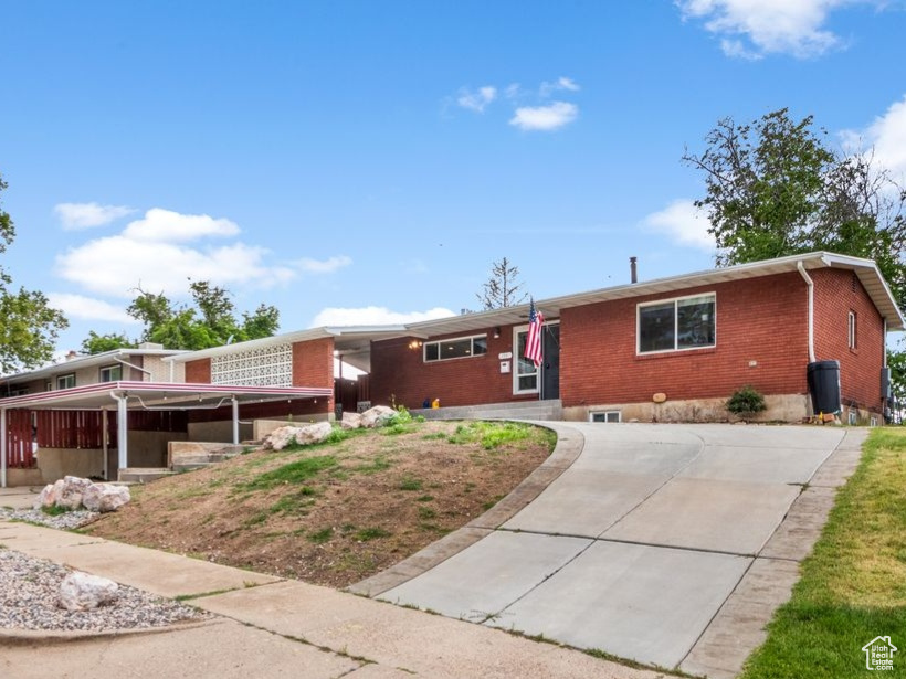 Ranch-style home featuring brick siding, concrete driveway, and a front yard