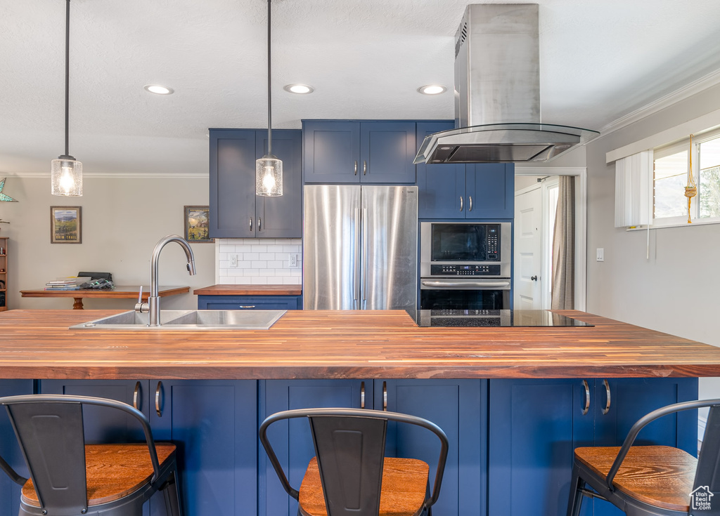 Kitchen with butcher block countertops, island range hood, black appliances, crown molding, and blue cabinets