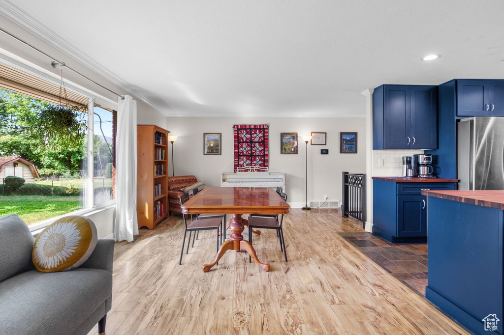 Dining space featuring ornamental molding, light wood-style floors, and recessed lighting