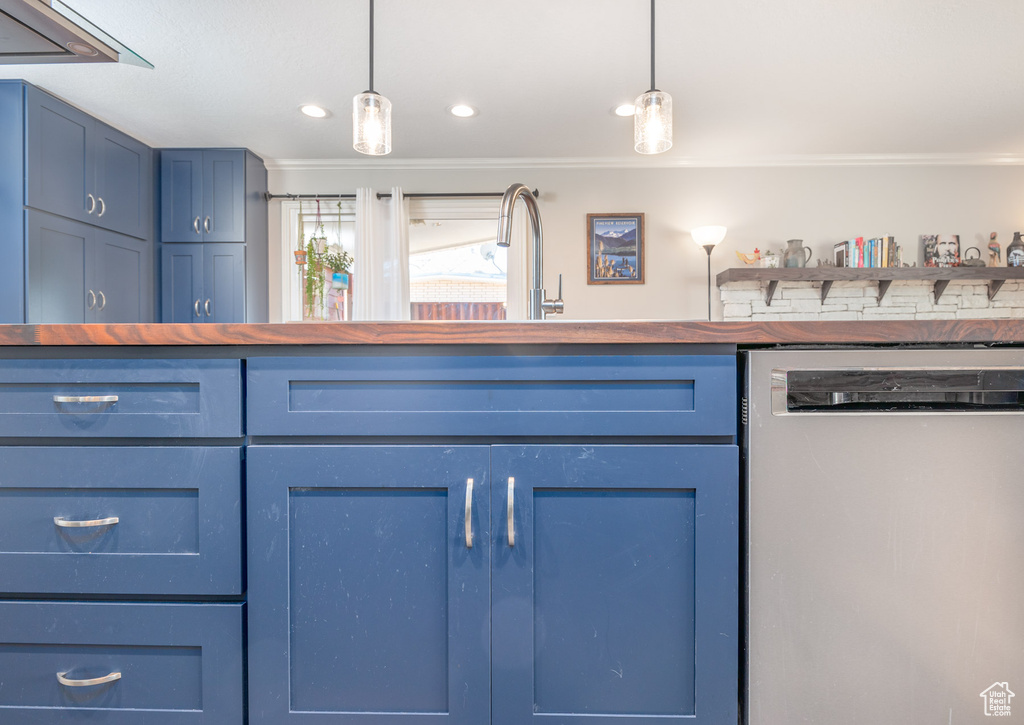 Kitchen with dishwashing machine, ornamental molding, blue cabinets, butcher block counters, and decorative light fixtures