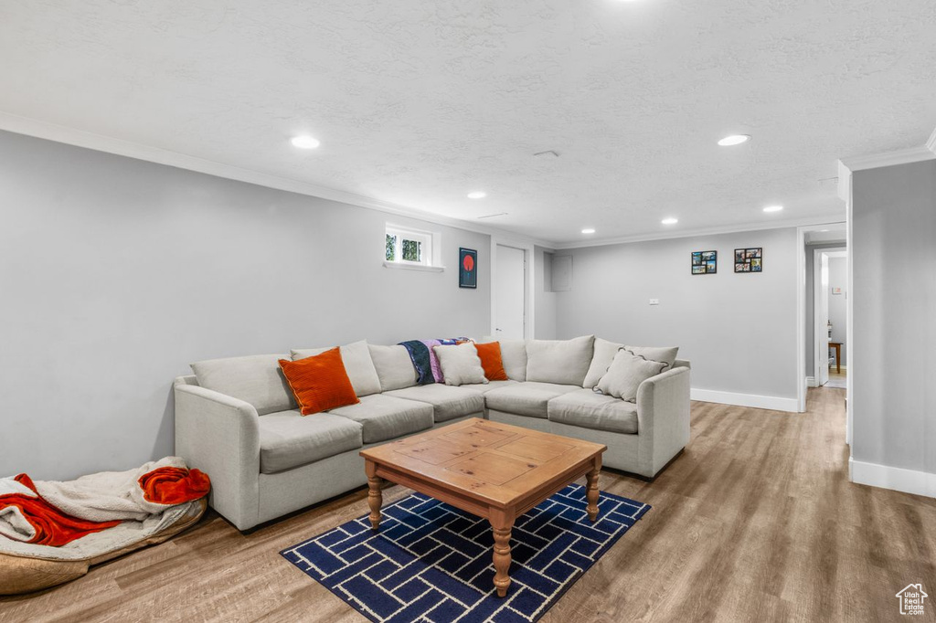 Living room with crown molding, wood finished floors, and recessed lighting