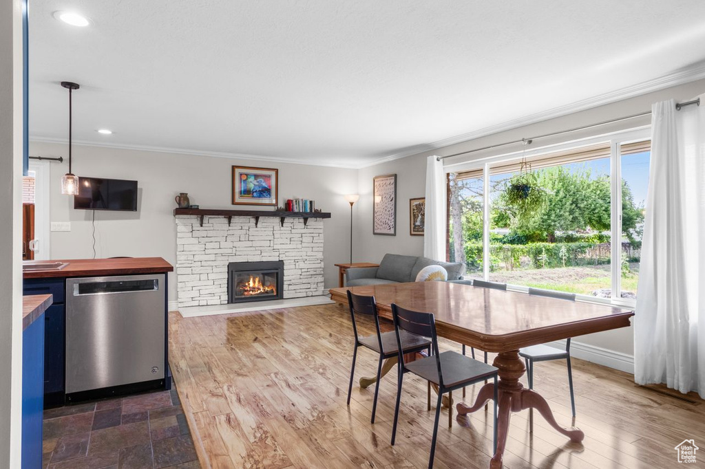Dining space with ornamental molding, a stone fireplace, recessed lighting, and dark wood finished floors