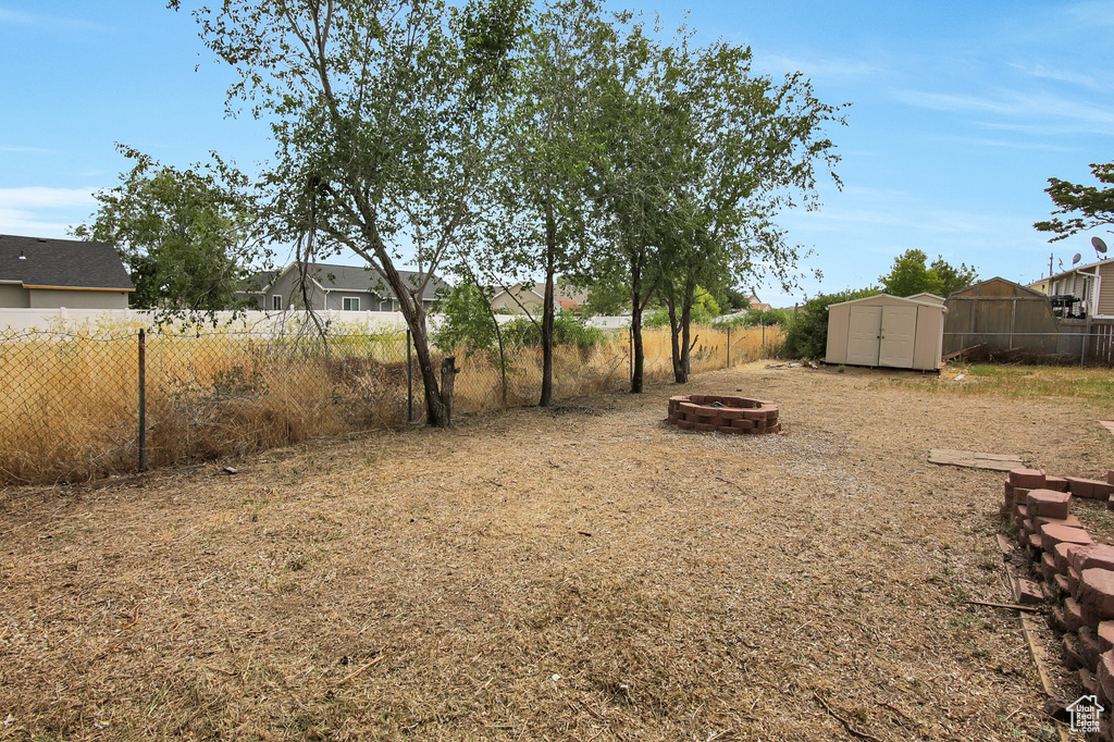 Fenced backyard with an outdoor fire pit and a storage unit