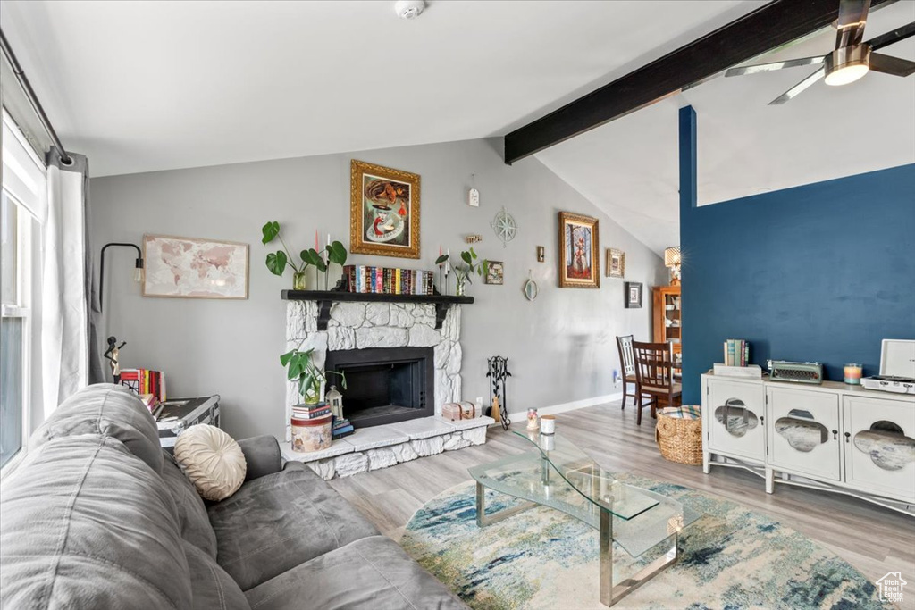 Living area with wood finished floors, ceiling fan, and a stone fireplace