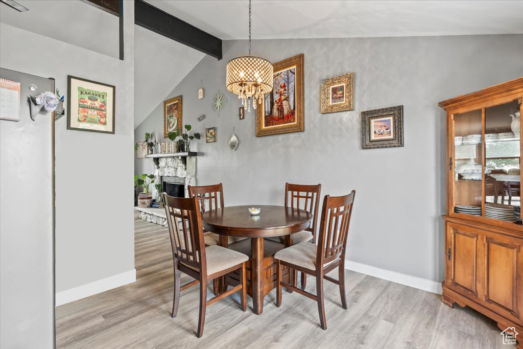 Dining space featuring light wood-style floors, a chandelier, and a fireplace