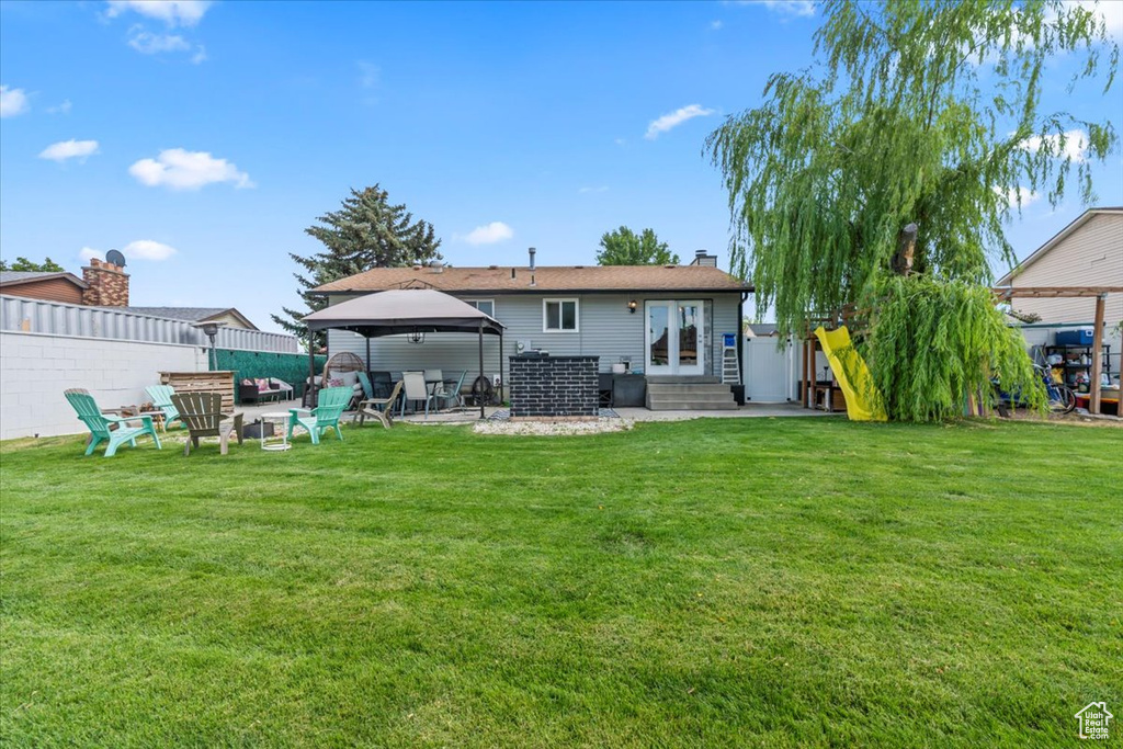 Rear view of property with a gazebo, entry steps, a chimney, and a patio area