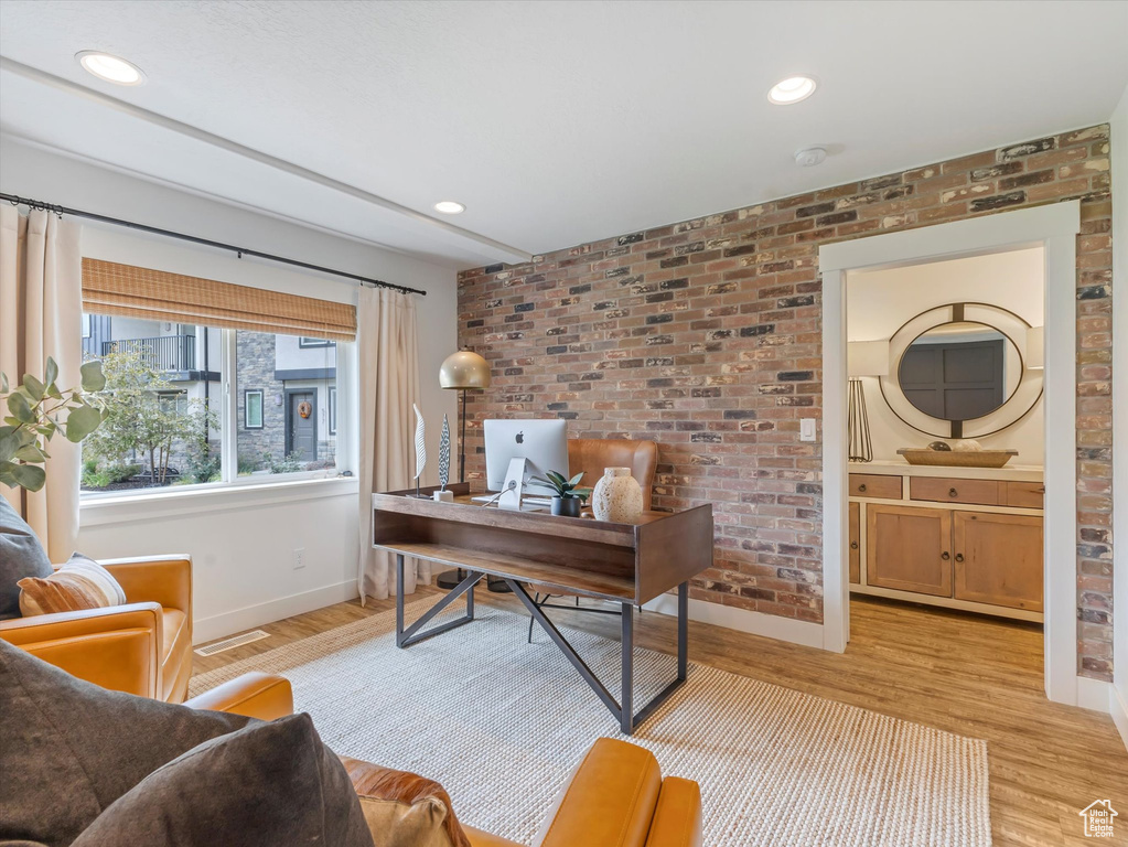 Office space featuring light wood-style flooring, recessed lighting, and brick wall