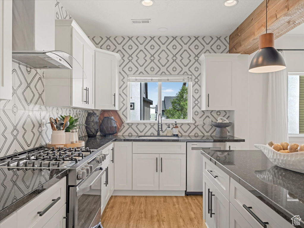 Kitchen with stainless steel appliances, wall chimney range hood, plenty of natural light, light wood-style flooring, and recessed lighting