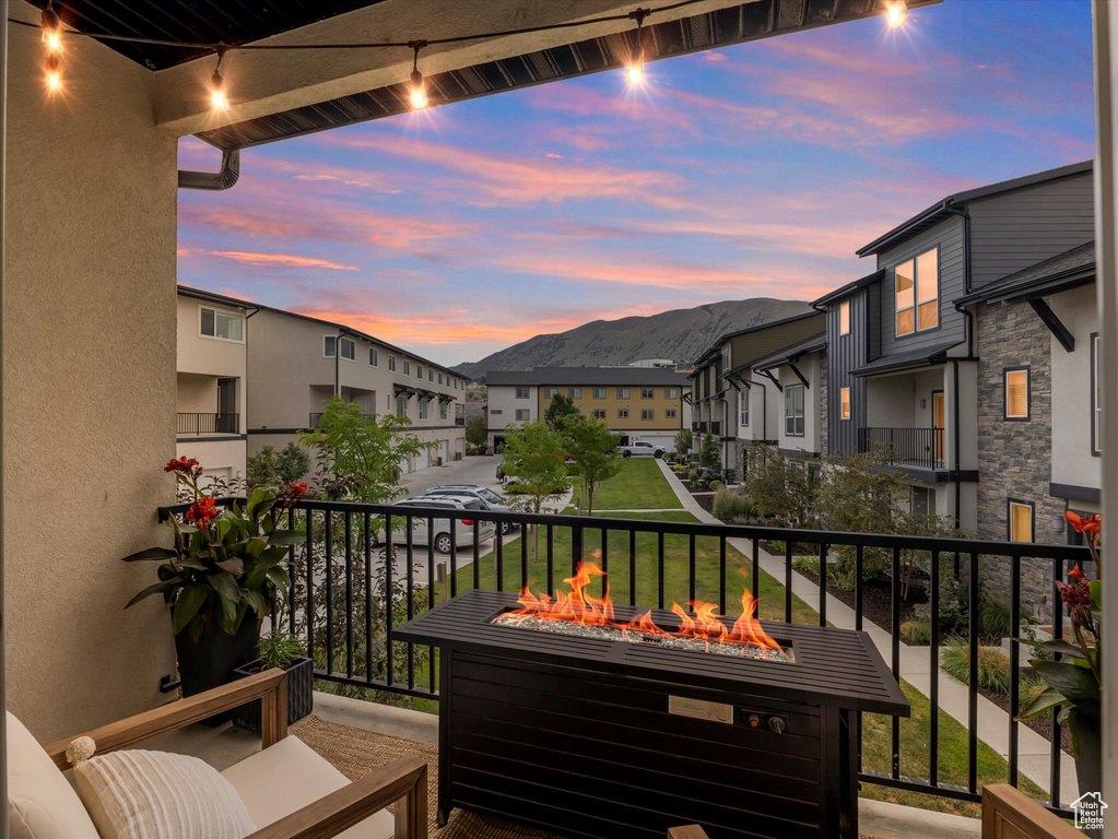 Balcony at dusk featuring an outdoor fire pit, a residential view, and a mountain view