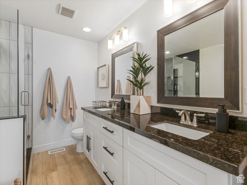 Bathroom featuring double vanity, wood finished floors, and a shower stall