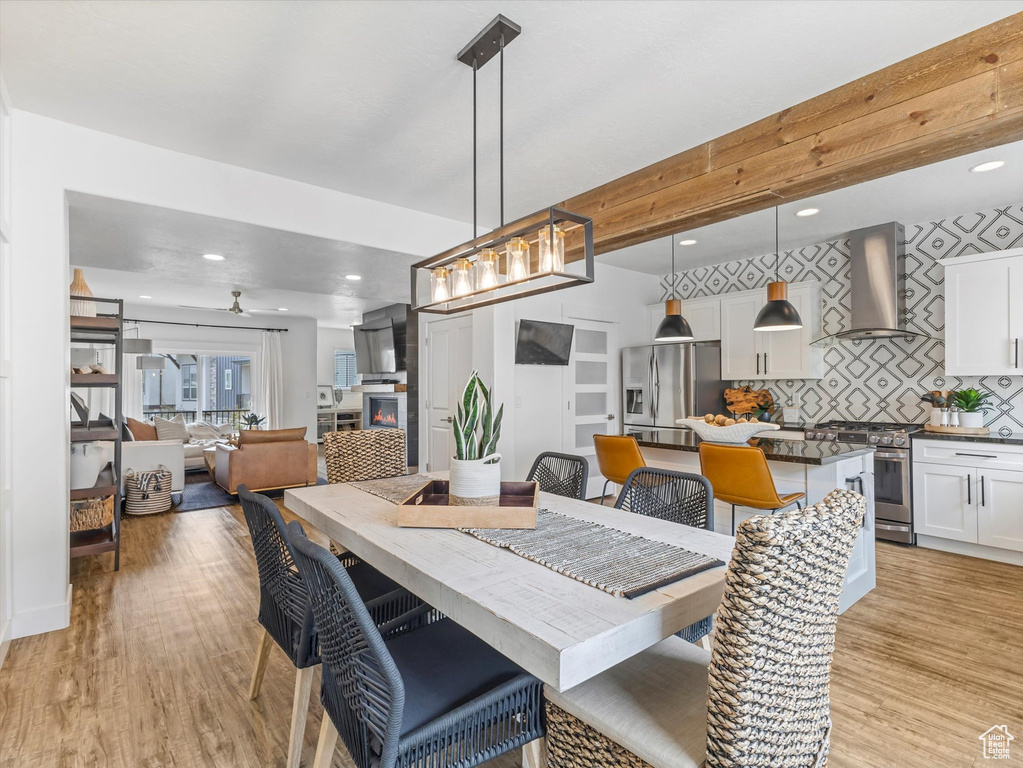 Dining space featuring light wood-style flooring, a glass covered fireplace, recessed lighting, and ceiling fan