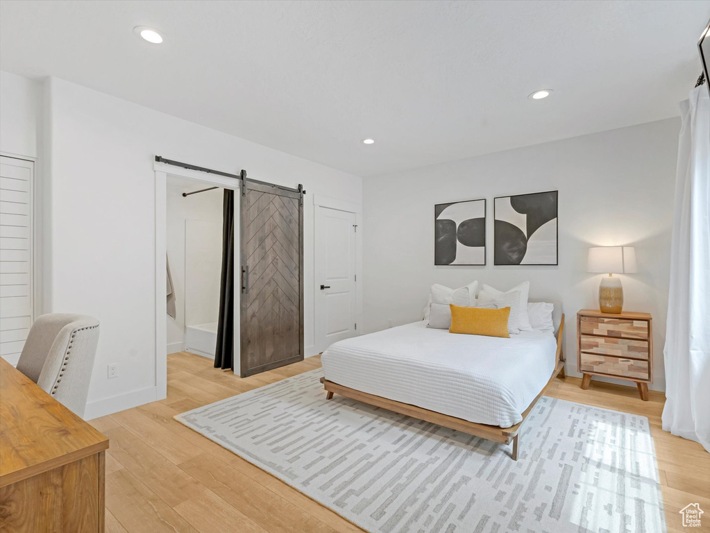 Bedroom featuring a barn door, light wood-type flooring, and recessed lighting