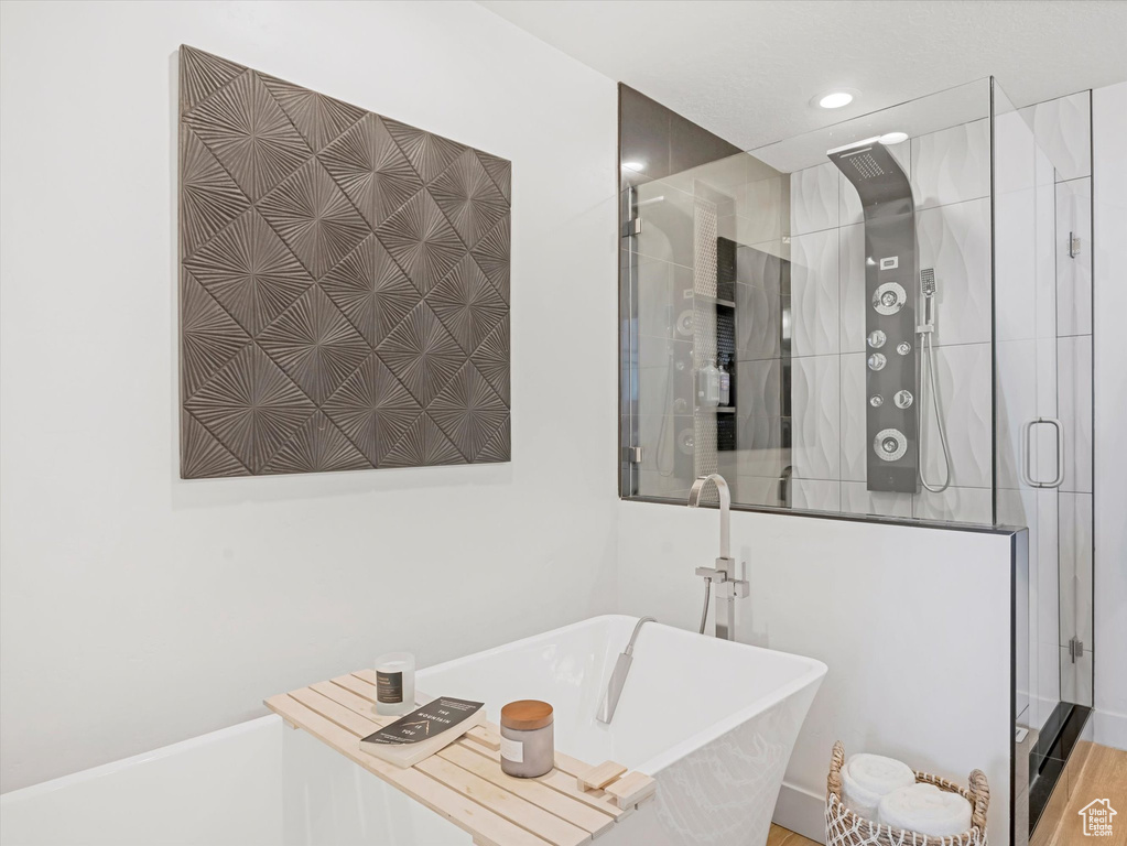 Bathroom with a stall shower, a freestanding tub, and recessed lighting