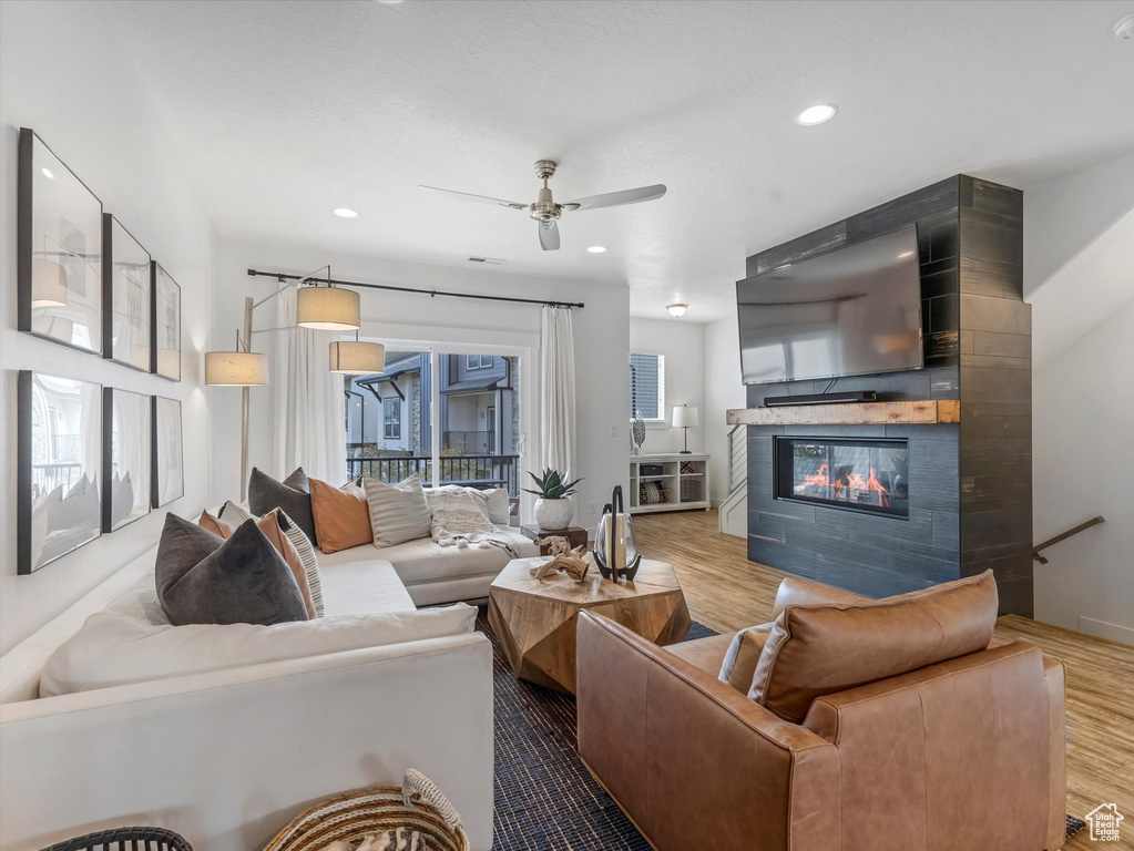 Living area with a ceiling fan, wood finished floors, a large fireplace, and recessed lighting