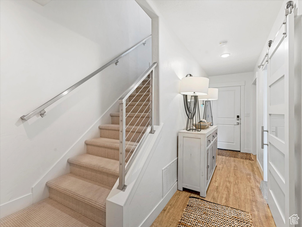 Staircase with a barn door and wood finished floors