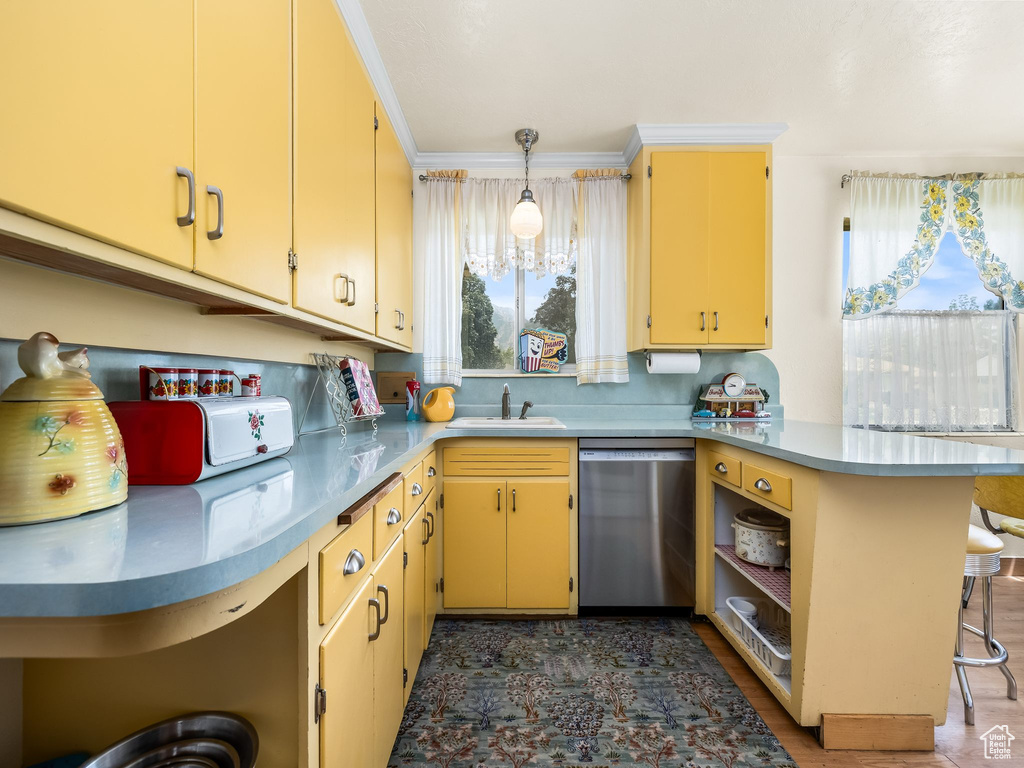 Kitchen featuring stainless steel dishwasher, a peninsula, a kitchen bar, crown molding, and backsplash
