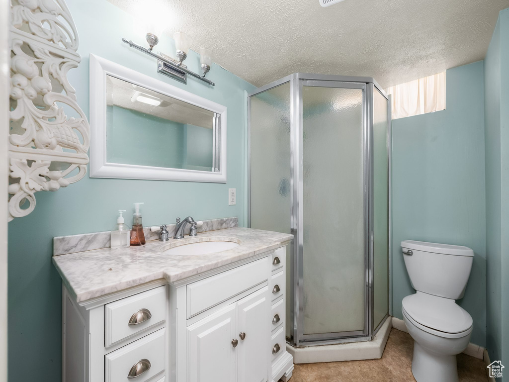 Full bath featuring vanity, a textured ceiling, and a stall shower