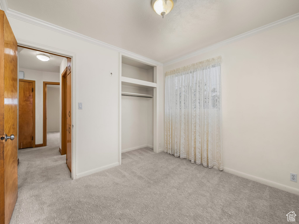 Unfurnished bedroom with carpet flooring, ornamental molding, and a closet