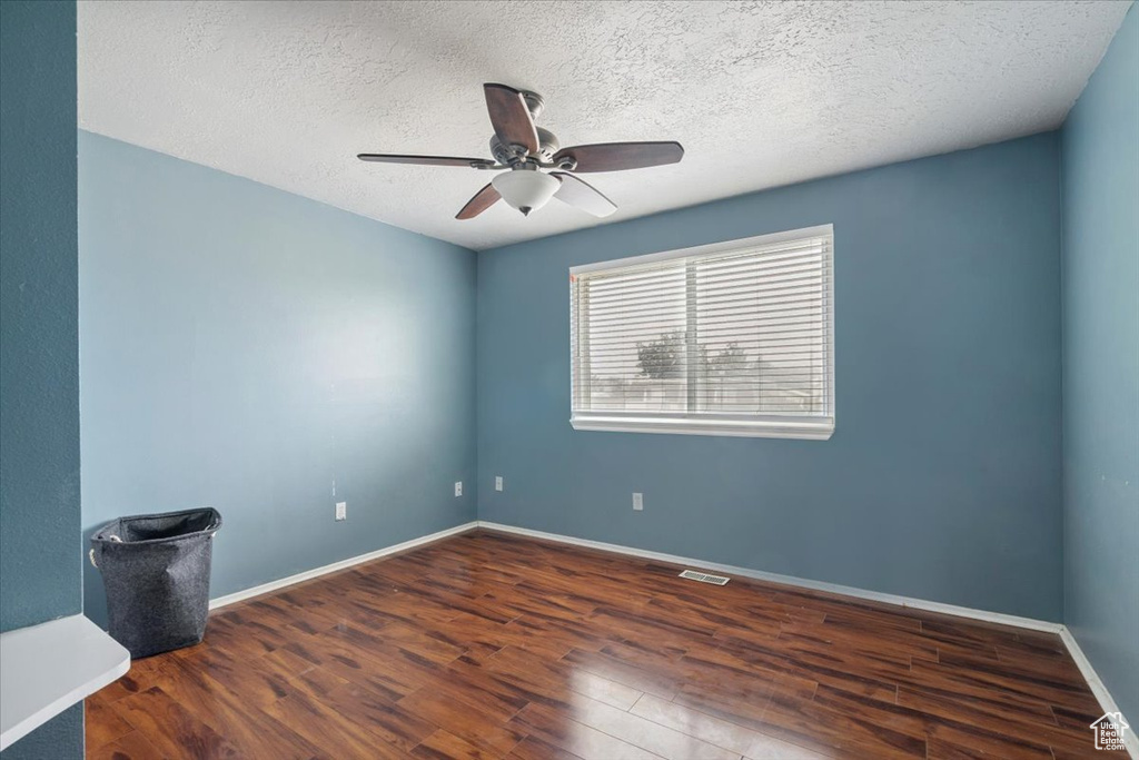 Spare room with wood finished floors, ceiling fan, and a textured ceiling