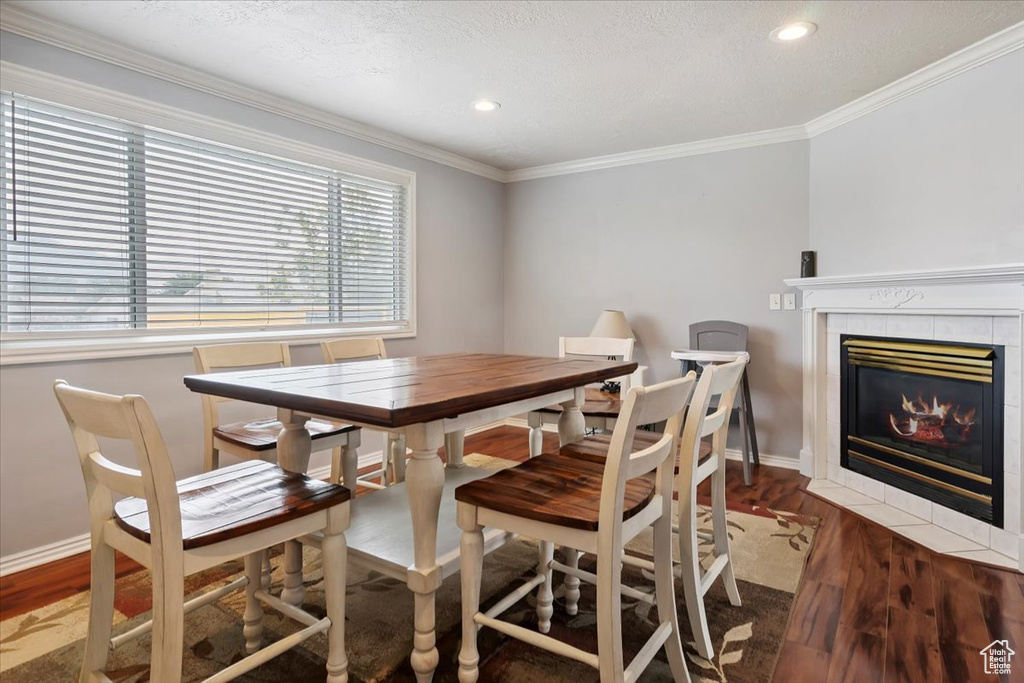 Dining room featuring ornamental molding, wood finished floors, a fireplace, recessed lighting, and a textured ceiling