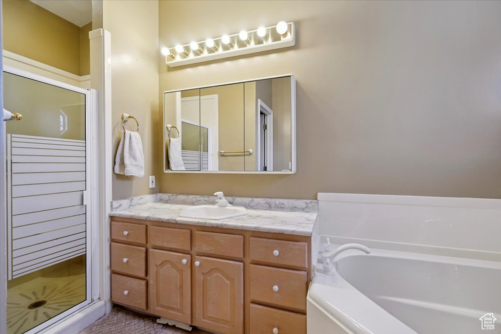 Bathroom featuring a shower stall, vanity, and a garden tub